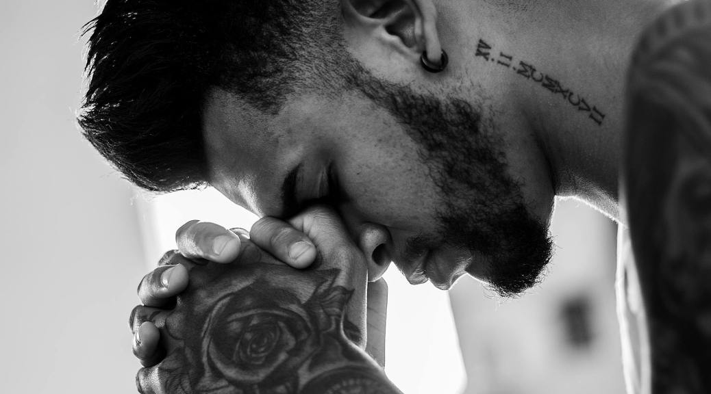 man tattooed praying